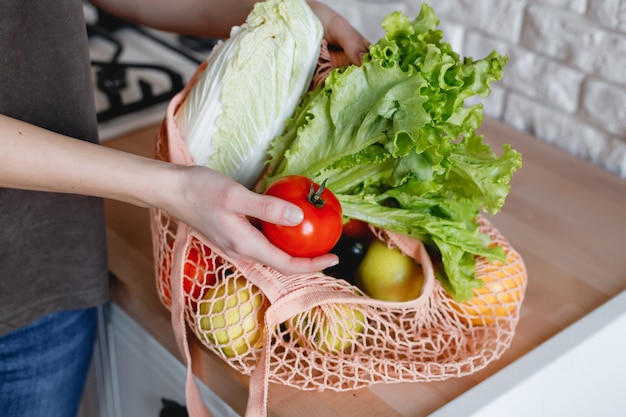 Vrouw houdt tas met groenten en fruit in de keuken