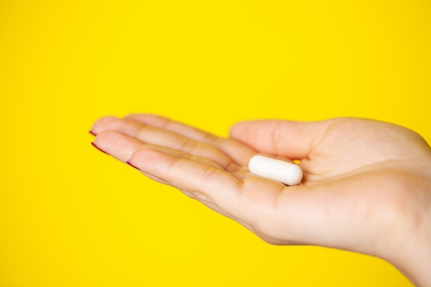 Vrouw houdt witte pil in haar hand voor gewichtsverlies