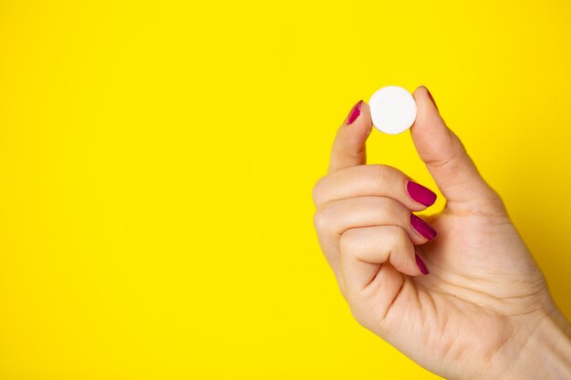 Vrouw houdt witte pil in haar hand voor gewichtsverlies