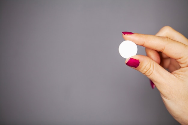 Vrouw houdt witte pil in haar hand voor gewichtsverlies.