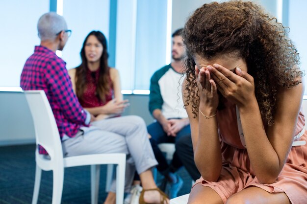 Vrouw huilen terwijl creatieve business team achter op kantoor