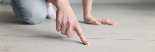 Vrouw huisvrouw wijzende vinger naar vuil op de vloer met laminaat close-up kwaliteitsreiniging van