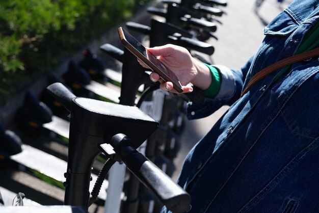 Vrouw huren scooter met app op haar mobiele telefoon close-up kicksharing scooter verhuur concept