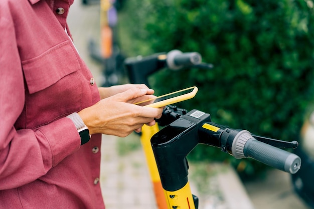 Vrouw huurt een elektrische scooter via een app op haar mobiele telefoon