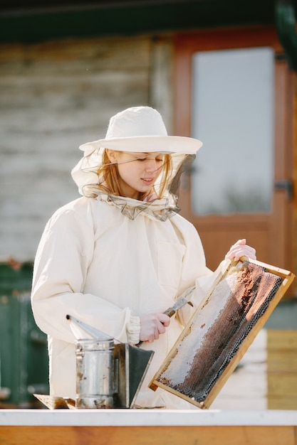 Vrouw imker zorgt voor bijen. Het dragen van een overall vrouw werkt bij de bijenstal.