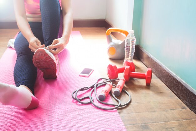 Vrouw in activewear bindende schoenen op sportmat, Training of oefening