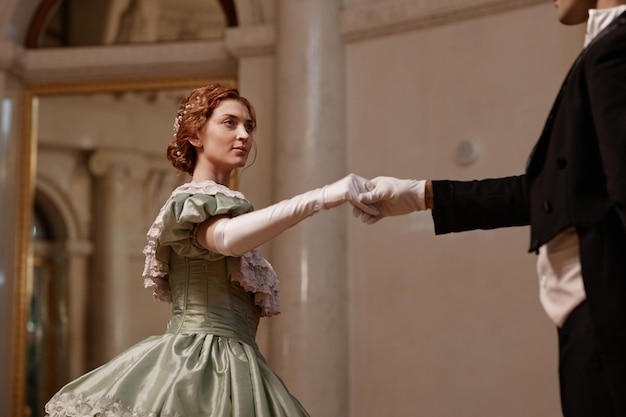 Foto vrouw in baljurk danst met een heer in het paleis.