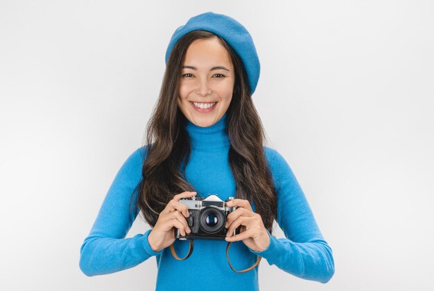 Vrouw in baret lachen en fotograferen op retro camera geïsoleerd op witte achtergrond