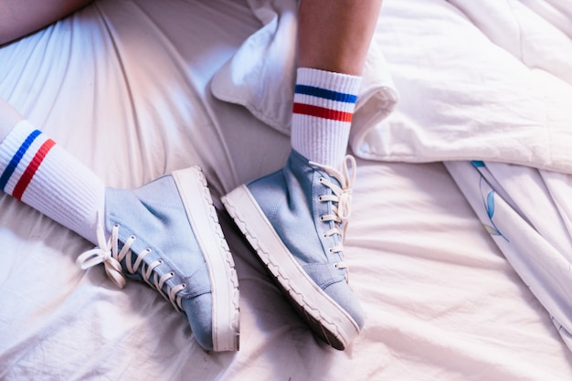 Vrouw in bed met blauwe pantoffels die thuis een boek beginnen te lezen