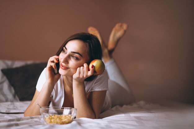 Vrouw in bed met telefoon en appel