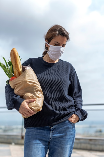 Vrouw in beschermend masker dat met aankoop naar huis komt