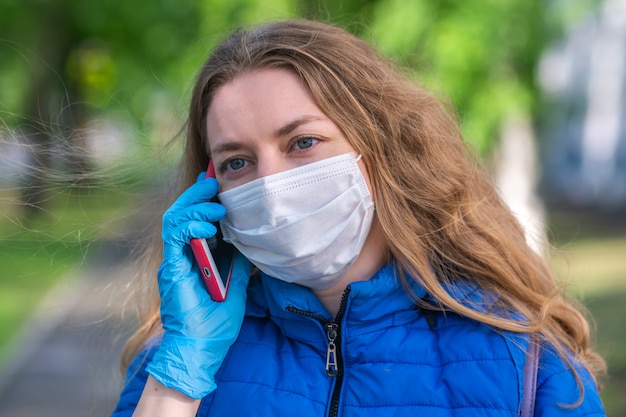 Vrouw in beschermend masker en handschoenen praten aan de telefoon