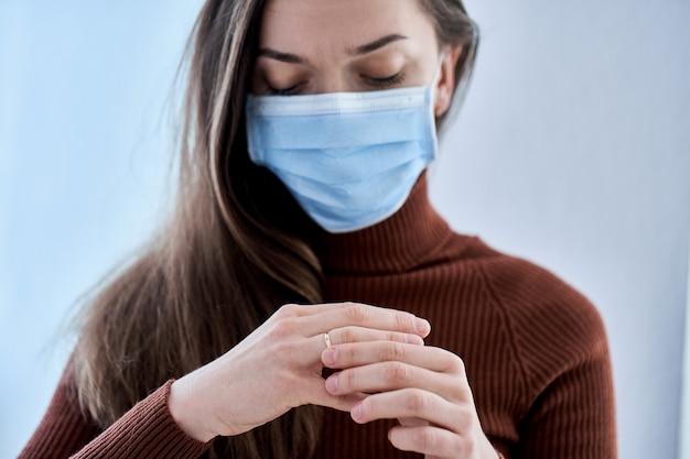 Vrouw in beschermend masker ring uit vinger verwijderen. Verbreek de relatie en de scheiding na samenwonen tijdens quarantaine en isolatie als gevolg van coronavirus covidepidemie. Echtscheiding concept