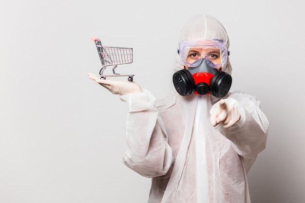 Foto vrouw in beschermend pak en bril met masker houdt winkelwagentje