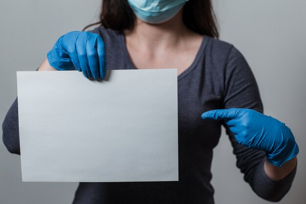 vrouw in beschermende handschoenen en een masker wijst een vinger op het lege bordje