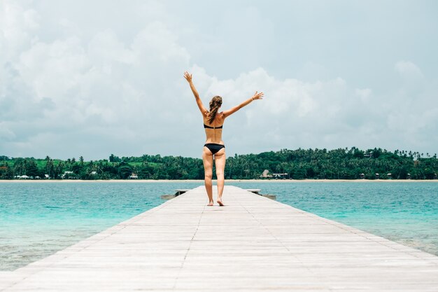 Vrouw in bikini die langs een tropische steiger loopt