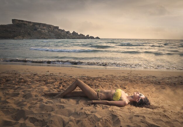 vrouw in bikini liggend op het strand