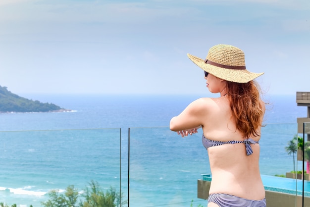 Vrouw in bikini staat aan de rand van het zwembad