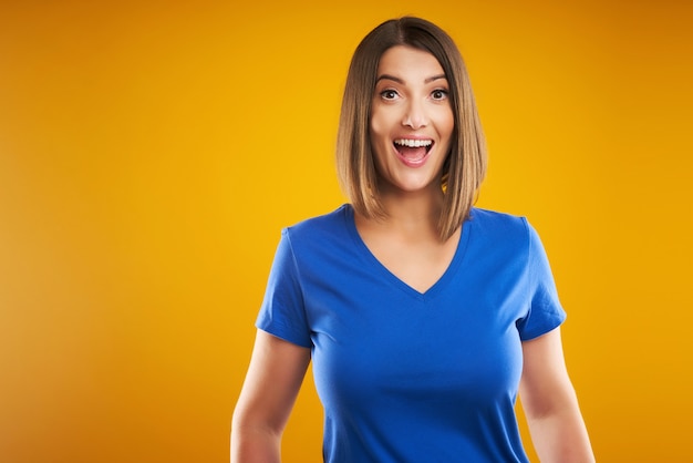 vrouw in blauw t-shirt camera kijken over gele achtergrond