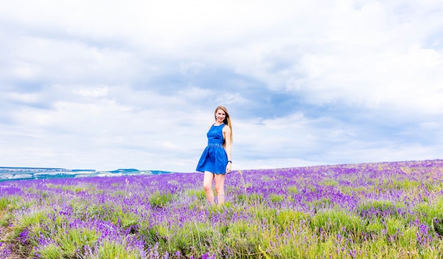 vrouw in blauwe jurk op lavendel veld bij bewolkt weer.