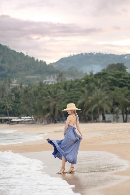 Vrouw in blauwe jurk pose op het strand.