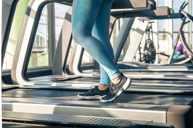 Foto vrouw in blauwe leggings staat op een loopband