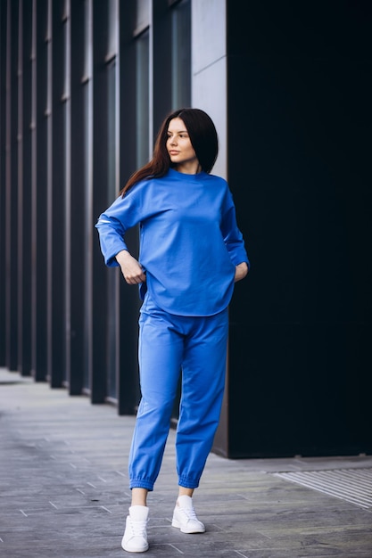 Vrouw in blauwe sportkleding die buiten bij het gebouw staat