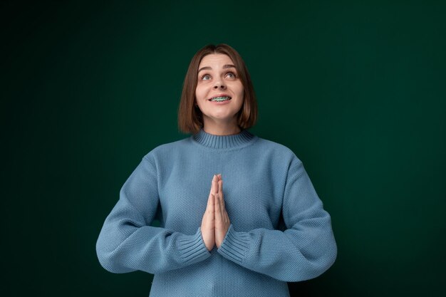 Vrouw in blauwe trui voor de groene muur.