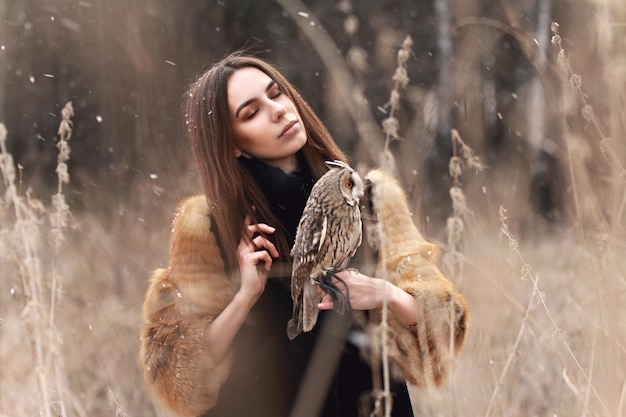 Vrouw in bontjas met uil hand eerste herfst sneeuw