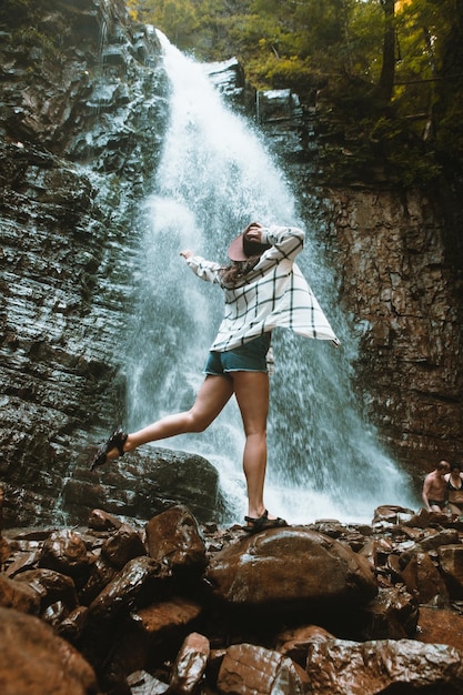 Vrouw in bruine hoed genietend van uitzicht op waterval