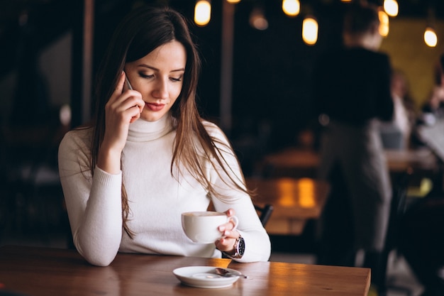Vrouw in café met telefoon en koffie