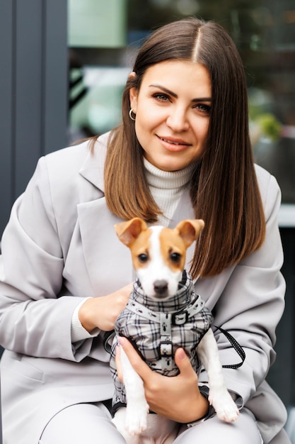 Vrouw in casual jasje knuffelt haar pluizig getrainde rasechte Jack Russell Terrier-hond