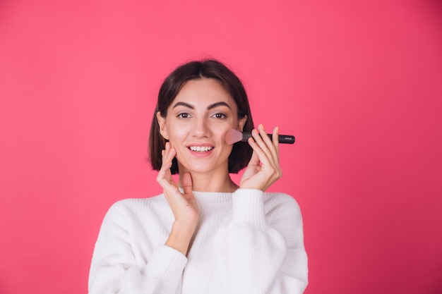 Vrouw in casual witte trui op rode muur