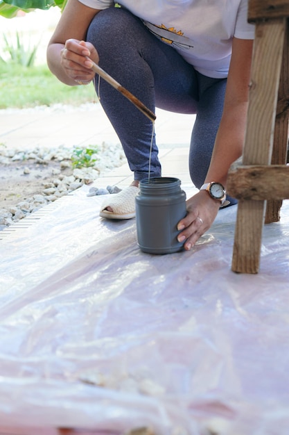 Vrouw in de achtertuin maakt een stoel klaar voor restauratie terwijl ze een beschermende tape in haar hand houdt