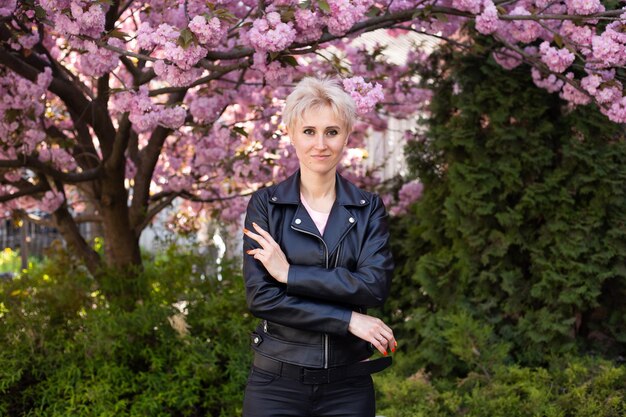 Vrouw in de buurt van roze sakura bloeiende boom