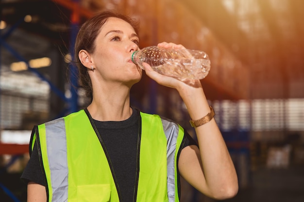 Vrouw in de gezondheidszorg die schoon water drinkt terwijl ze op een warme plek werkt voor verfrissing en persoonlijke gezondheid