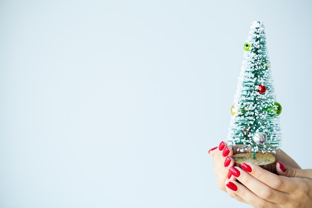 Vrouw in de hand houdt kerstversiering op lichte achtergrond.