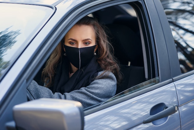 Vrouw in de stad. persoon in een masker. coronavirus-thema. vrouw bij de auto.