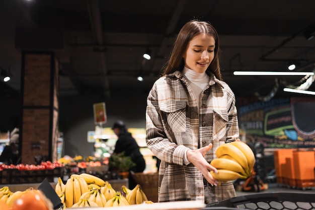 Vrouw in de supermarkt koopt bananen