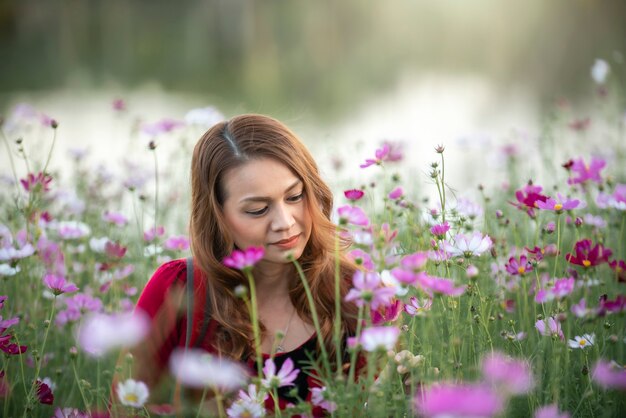 Vrouw in de tuin bloemen Kosmos bloemen om haar aan te raken. Op een heldere dag