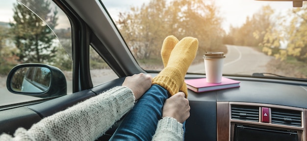 Vrouw in een auto in warme wollen gele sokken op het autodashboard