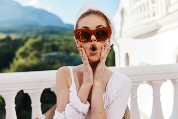 Vrouw in een badjas met zonnebril zit op een open balkon Perfecte zonnige ochtend