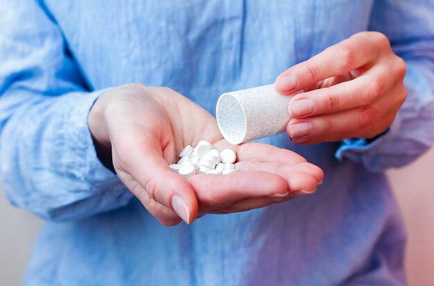 Foto vrouw in een blauwe blouse giet pillen uit een fles in haar hand neemt antibiotica antidepressiva