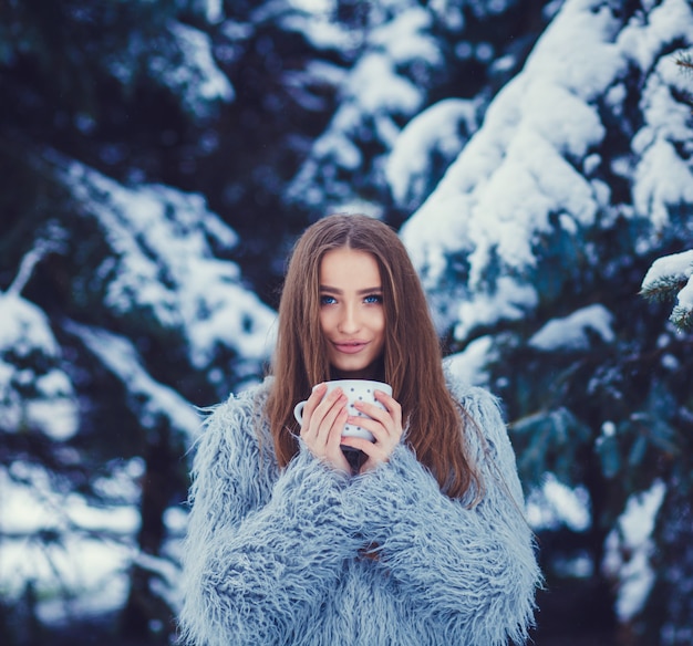 Vrouw in een blauwe bontjas drinkt thee