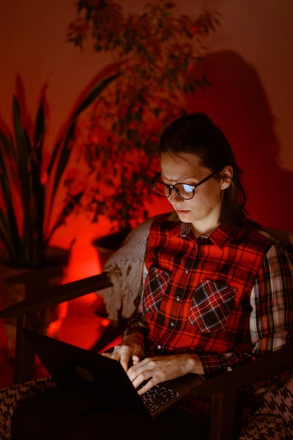 Vrouw in een donkere kamer werkt op een laptop of kijkt een film en speelt videogames als freelancer