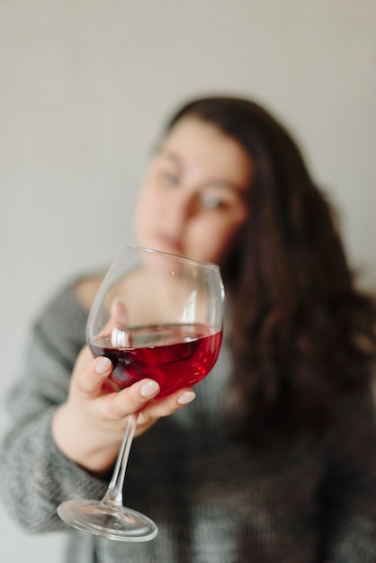 Vrouw in een grijze trui met een glas rode wijn