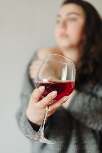 Vrouw in een grijze trui met een glas rode wijn