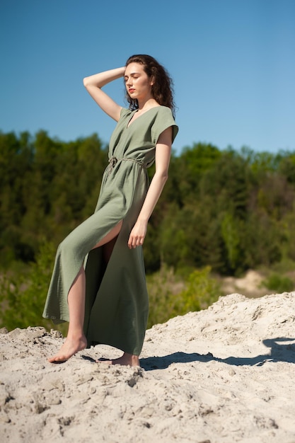 Vrouw in een groene jurk staande op een zandduin