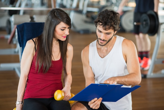 Vrouw in een gymnastiek die haar programma leest