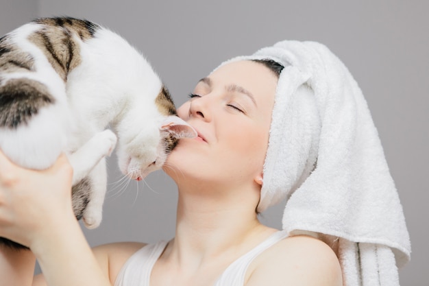 vrouw in een handdoek op haar hoofd met een kat op een licht